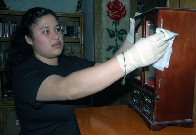 Marysville YMCA Minority Achievers Program teen volunteer Leticia Aparicio dusts off the bedroom keepsakes of Arlington disabled senior Sandee Wynkoop on Jan. 28.