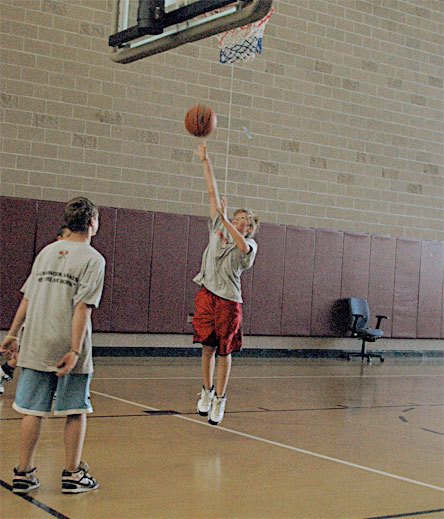 Seventh-grader Landon Riker makes a one-handed shot during a basketball camp for beginning and intermediate players at the Navy Exchange. The camp begins with 100 shots as players work on developing their skills and their basketball IQ.