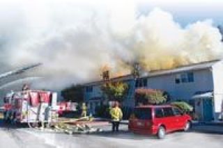 Smoke billows from the attic of Building J as Marysville firefighters work to cut holes in the roof of the Westwood Crossing town homes on Sept. 6.
