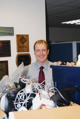 Jeff Olsen of Whitfields Insurance stands in front of boxes of donated cell phones the company is collecting during October. Working phones are given to women at risk for emergency use; the others are recycled