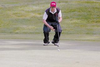 Freshman golfer Brandon Caldwell crouches to line up his putt on the back nine of Kayak Point Golf Course.