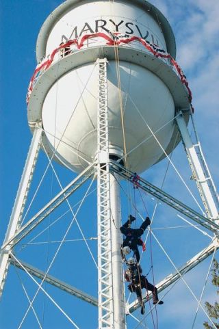Marysville firefighters Chad Hale and Todd Furness simulate rescuing an unconscious and stranded worker hanging from the water tower during a demonstration at the Aug. 1