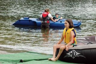 McKenna Dahl waits for fellow campers to don their swimwear and join her on an inner tube ride around Flowing Lake. Other campers enjoy using motorized kayaks to buzz around the lake.