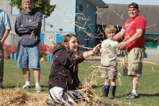 Syndy Lee Blair makes some hay fly while the sun shines during a dirt bike competition at the Marysville YMCA on Sept. 8.  Blair was one of seven riders in the finals of the National Youth Program Using Minibikes Rodeo held at Allen Creek Elementary School.  She was searching for a t-shirt buried in the hay during an agility course.