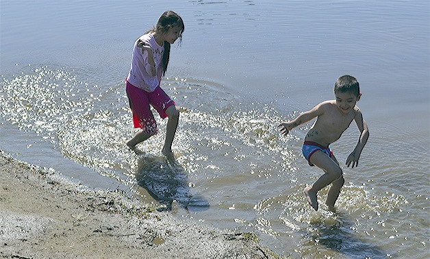Eileen starts to throw wet sand at her little brother Roberto Chavez Jr. at Twin Lakes Park near Lakewood Thursday. They were with their family enjoying the sun.