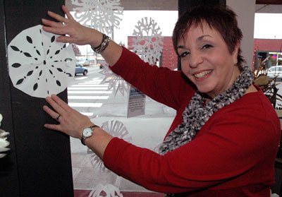 Mary Kirkland of Hilton Pharmacy places hand-cut paper snowflakes from her customers on her store’s walls as part of ‘Snowflake Saturday’ on Dec. 14.