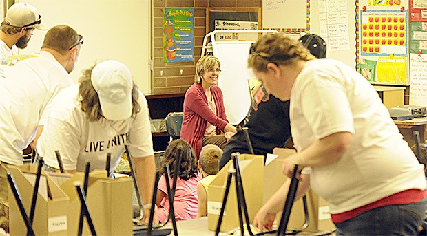 United Way Days of Caring volunteers from The Everett Clinic clean the bottom of students' chairs as class goes on at Pinewood Elementary School Sept. 12.