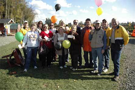 Representatives of the Marysville School District are flanked by members of the Marysville Noon Rotary as they brandish their checks from 'Pumpkins for Literacy' at the Smokey Point Plant Farm Oct. 25
