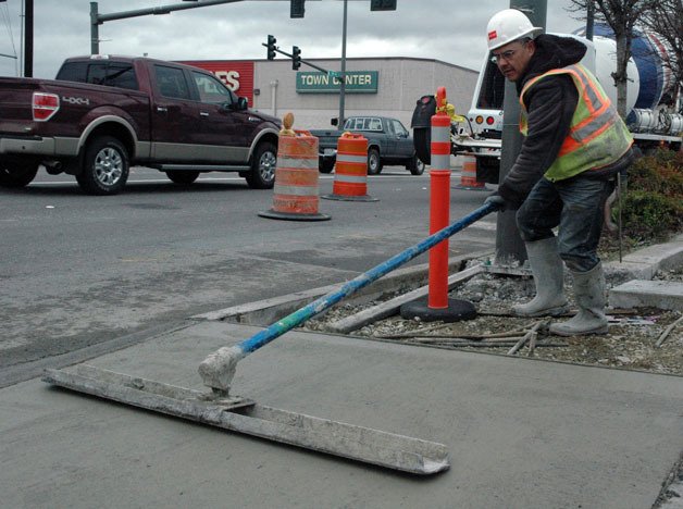 Construction worker Sergio Rojas puts the finishing touches on a stretch of sidewalk leading to the new Ebey Slough Bridge.