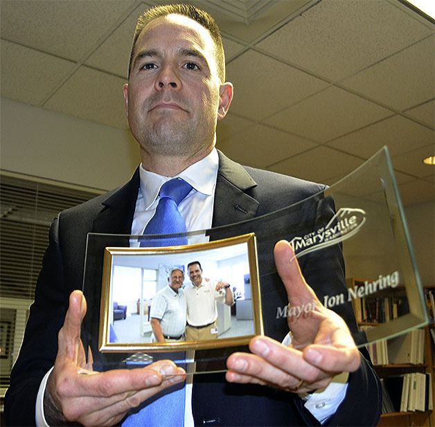 Marysville Mayor Jon Nehring holds a photo he keeps in his office of himself and previous mayor Dennis Kendall