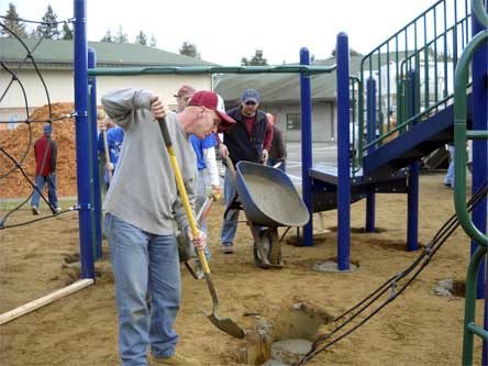 Kris Edge shovels concrete into the playground’s spin-bar hold.