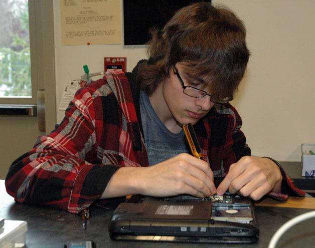 Marysville Arts & Technology High School junior Mason Totten examines the inner workings of a malfunctioning laptop during the school’s repair lab class.