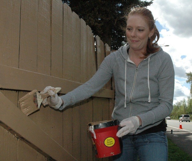 Leah Ingram applies a second coat to cover the graffiti on a 51st Avenue fence on April 26.