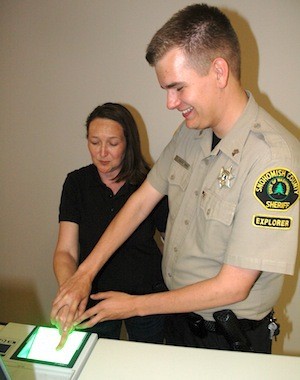Sheriff’s spokesman Shari Ireton gets her finger printed by police explorer Charles Southward at the open house.