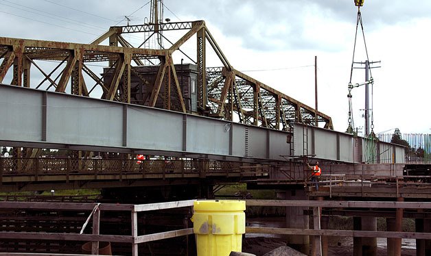 Construction crews use cranes to install segments of the new Ebey Slough Bridge’s girders on June 14.