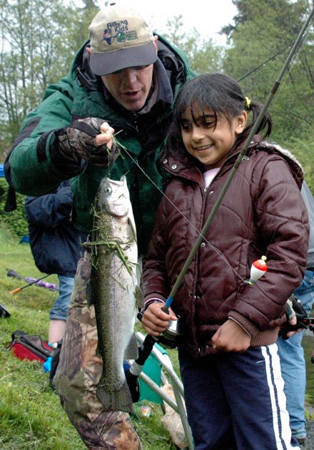 Eight-year-old Trina Davis looks at a trout she just caught as Barry Martin of the Everett Steelhead and Salmon Club congratulates her during the annual fishing derby at Jennings Memorial Park May 1.