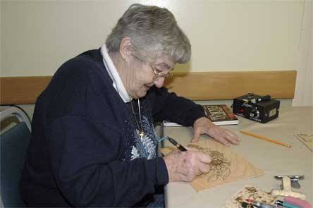 Barbara Faries feels more comfortable with wood-burning art than with woodcarving because she doesn’t like knives.