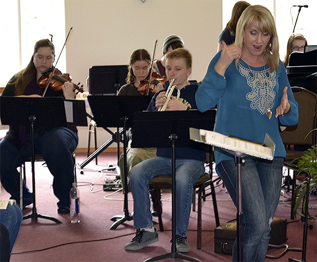Choir director Summer Long energizes the band and choir during rehearsal of 'The Story.'