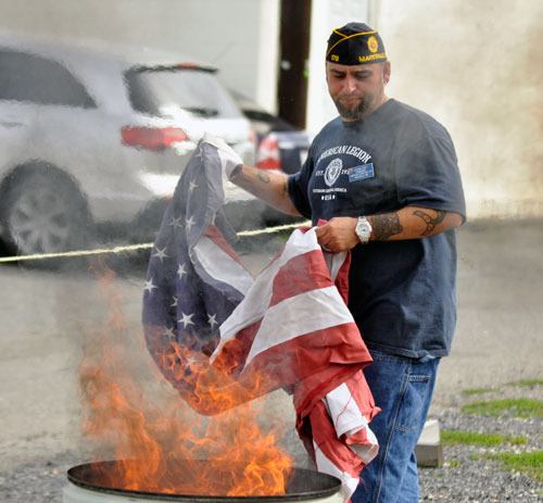 Legion Post 178 Cmdr. Jeremiah Fort honorably retires an American flag during a ceremony on Saturday