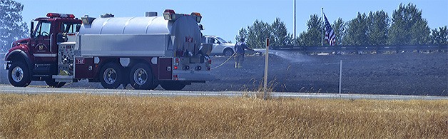 Firefighters from Fire District 17 hose down a dry grass fire on the offramp at I-5 going on to Fourth Street in Marysville about 1:30 this afternoon (June 30). Flames shot up as high as 20 feet in nearby trees for a short period of time. Cause of the fire was unknown.