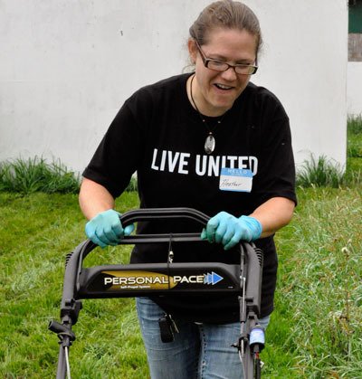 Volunteer Heather Hopingardner mows overgrown grass at the All-Breed Equine Rez-Q for United Way of Snohomish County’s annual Day of Caring.