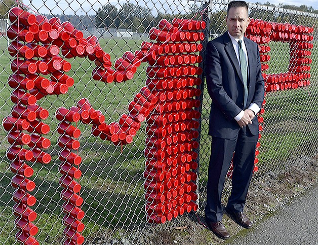 A solemn Mayor Jon Nehring stands along with fence at Marysville-Pilchuck High School