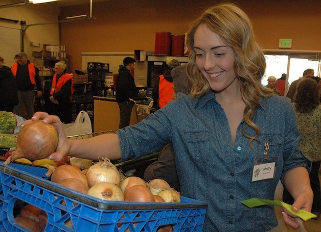 Lakewood High School junior Molly Stuller picks out produce for a client at the Marysville Community Food Bank on Nov. 22.