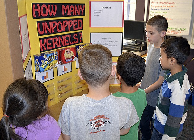 Tyler Crawford explains his science project about popping popcorn to fellow students.