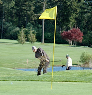 M-P senior Sara Rott fishes the ball out of the sand trap in her second stroke on the par three ninth hole and lands it on the putting green.