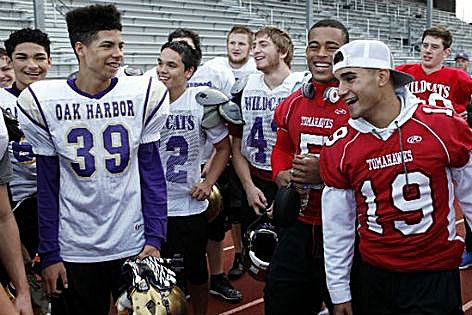Players on the Oak Harbor and Marysville-Pilchuck football teams are all smiles Wednesday. Oak Harbor decided to forfeit its game last week against M-P after the shooting in a show of sportsmanship. M-P decided to return the favor by giving the league championship trophy to Oak Harbor.