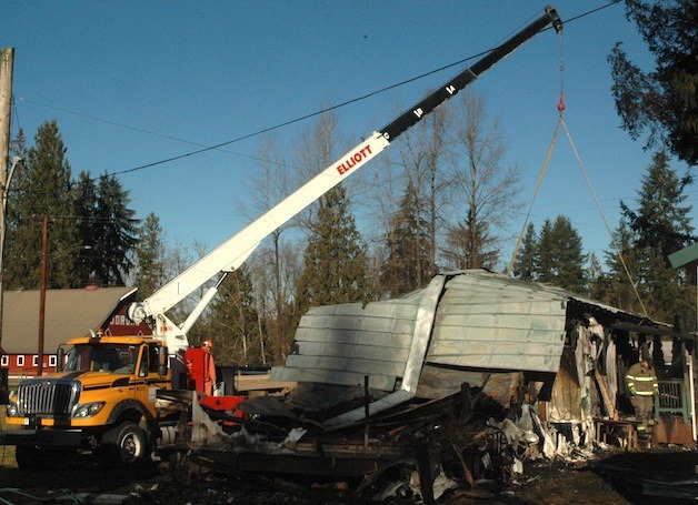 Crews stabilize the roof of the burned-out mobile home at 16400 Jordan Way so that investigators can enter Jan. 20.