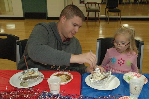 Joshua Williams helps prepare his daughter Makenzie's baked potato during the Marysville Family YMCA's Military Family Night on Nov. 16.