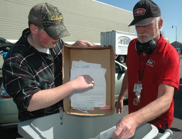 Tyler Holland of Marysville Getchell High School and Charles Wilson of the American Data Group shred documents April 18.