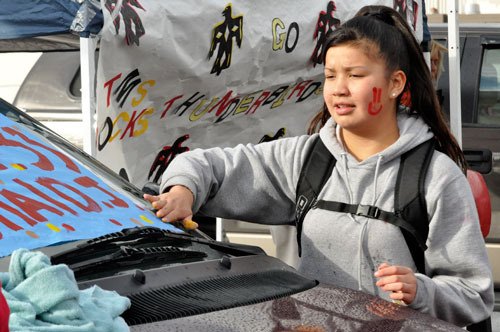 Paula Zackuse tapes a poster to the windshield of a car at a tailgate party for Totem Middle School’s last football game of the season. The Thunderbirds finished undefeated.