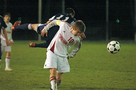 Senior forward Brady Ballew carries a leaping Everett defender on his back while heading the ball.