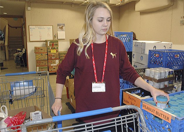 Volunteer Tori Anderson puts groceries in a cart at the Arlington Food Bank.