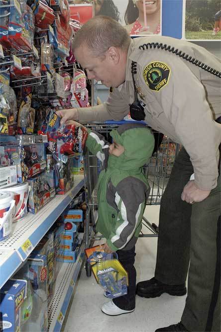 Marysville resident Jaiden Lynd-Stowers receives assistance in picking out toys from Snohomish County Sheriff’s Deputy Greg Sanders at the Quil Ceda Walmart.