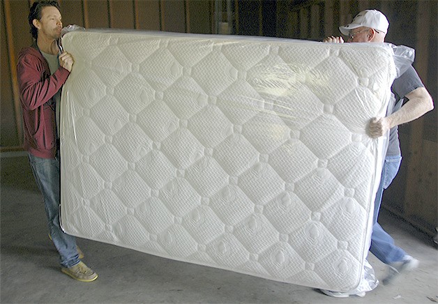Volunteers carry a mattress into the transitional house.