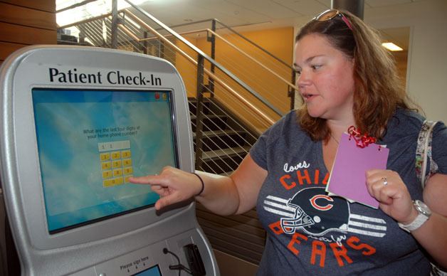 Marysville’s Kelly Marshall enters information into the keypad of the self-service kiosk at the Everett Clinic in Smokey Point on Aug. 25.