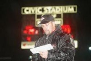 Coach Rudy Grandbois peers over his list of plays amid a pouring rainstorm Friday