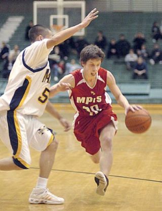 Marysville guard Ryan Lanphere drives past Mariner defender Danny Chhann in the second quarter of the loser-out district game on February 20.