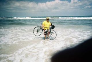 Rob Putnam holds his bike the in shallow waves of the Atlantic Ocean. This spring