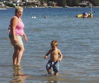 Jerin Wilson plays in the shallow water of the county park on Lake Goodwins north shore under his mothers watchful eye. The water gets no deeper than about two and a half feet all the way to the dock that borders the swimming area.