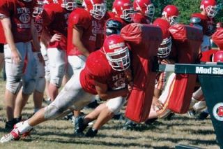 Tannen Hillis and his teammates use a blocking dummy to perfect their tackling skills during a hot afternoon practice.