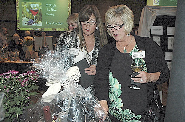 Kristin Van Loo and Diane Likes check out a wine basket at the Marysville Rotary's Nov. 7 auction.