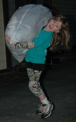 Everett Eagles Junior Drill Team member Cheyenne Gepner almost tips over from the weight of the clothes she carries to the Kloz 4 Kids offices on March 9.