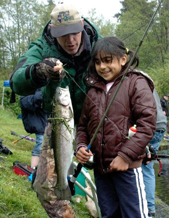 Trina Davis looks at a trout she just caught as Barry Martin of the Everett Steelhead and Salmon Club congratulates her during the annual fishing derby at Jennings Memorial Park last year.