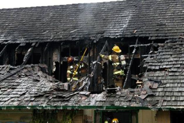 Captain Jason Schoonover and Fire Fighter Brien Gronemyer of the Marysville Fire District pull smoldering roofing material from a vacant home damaged by a Dec. 10 fire.