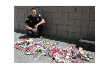 Marysville Police Officer Jake Robbins shows off some of the fireworks police confiscated in the days leading up to July 4. The items are mostly firecrackers and bottle rockets that are illegal to use in Marysville. Inset: This huge string of fireworks was laid out in a lot in the area of Grove Avenue. Police confiscated the string and charged the owner with a criminal offense.