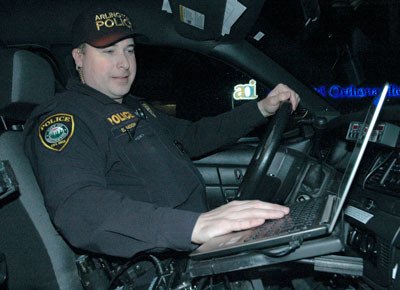 Arlington Police Officer Erik Moon checks his computer before driving his patrol car out for the ‘Night of 1